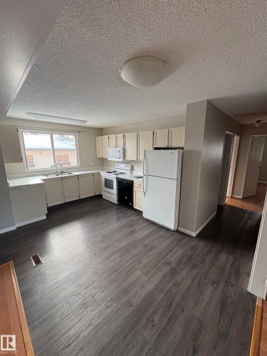 Kitchen featuring light countertops, white appliances, a textured ceiling, and dark wood finished floors - Edmonton, AB - Indoor Photo Showing Kitchen