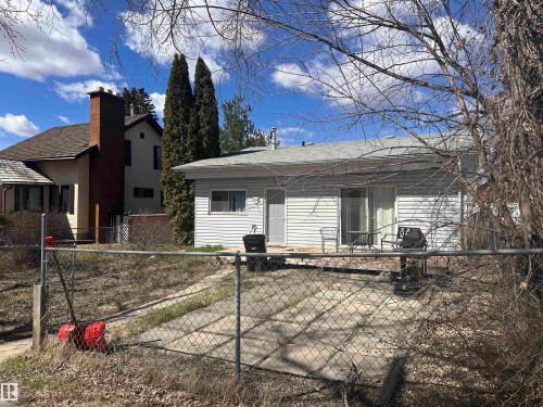 Rear exterior featuring light-colored siding, a sliding glass door, and an exterior door - 5128 52 Street, Barrhead, AB - Outdoor