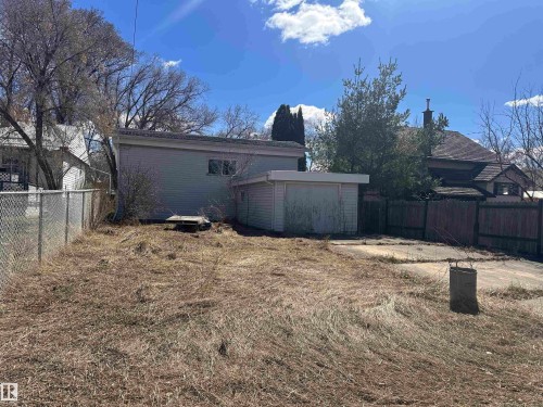 Expansive backyard featuring a chain-link fence, detached garage structure, and mature trees - 5128 52 Street, Barrhead, AB - Outdoor