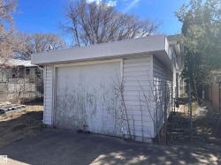 Detached garage with white siding and a flat roofline - 