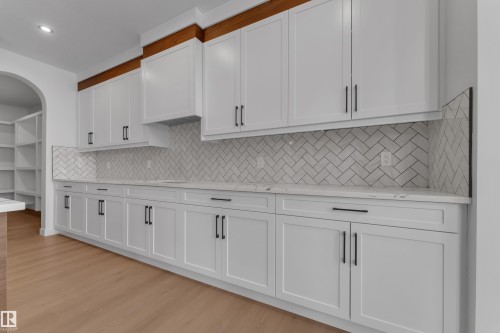 Kitchen with white cabinets, light stone counters, light wood-style flooring, backsplash, and recessed lighting - 40 Grayson Green, Stony Plain, AB - Indoor