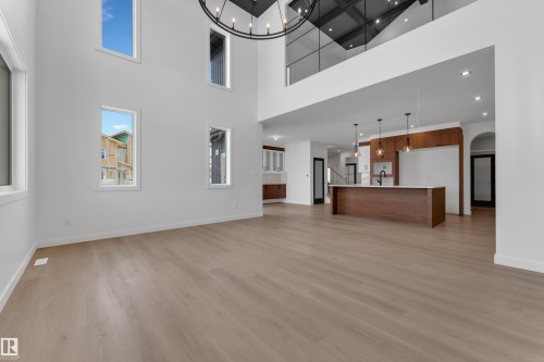 Unfurnished living room featuring hanging lights, light wood-type flooring, arched walkways, and a high ceiling - 40 Grayson Green, Stony Plain, AB - Indoor Photo Showing Other Room