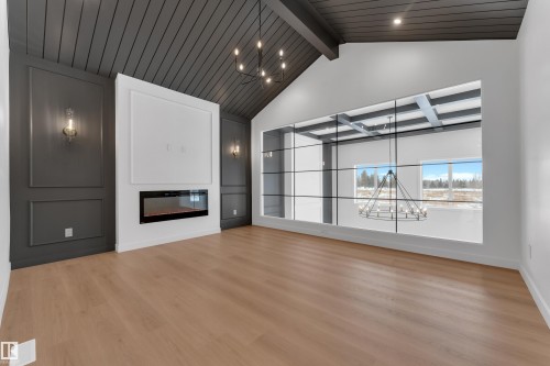 Unfurnished living room with a chandelier, a glass covered fireplace, and light wood-style flooring - 40 Grayson Green, Stony Plain, AB - Indoor With Fireplace