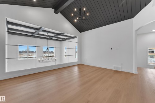 Empty room with a chandelier, light wood finished floors, arched walkways, healthy amount of natural light, and vaulted ceiling - 40 Grayson Green, Stony Plain, AB - Indoor Photo Showing Other Room