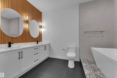 Full bath featuring a soaking tub, double vanity, and dark tile patterned floors - 40 Grayson Green, Stony Plain, AB - Indoor Photo Showing Bathroom