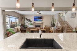 Kitchen with light stone counters, a ceiling fan, a fireplace, and pendant lighting - 