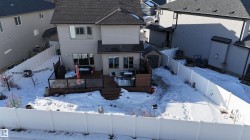 Snow covered property with a fenced backyard, a wooden deck, a storage unit, and a residential view - 