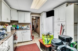 Kitchen featuring white cabinetry, a paneled ceiling, stainless steel dishwasher, and freestanding refrigerator - 