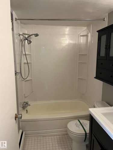 Full bathroom featuring shower / tub combination, vanity, baseboard heating, and light tile patterned flooring - 203 8524 Gateway Boulevard, Edmonton, AB - Indoor Photo Showing Bathroom