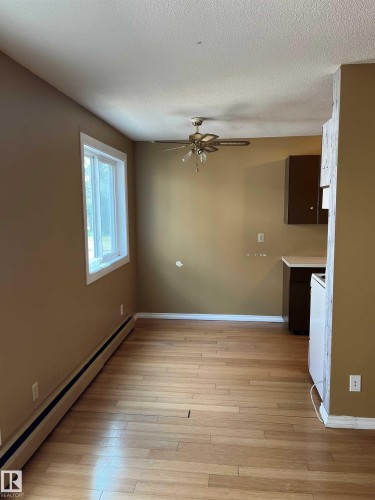 Unfurnished dining area featuring a baseboard heating unit, light wood-type flooring, a ceiling fan, and a textured ceiling - 203 8524 Gateway Boulevard, Edmonton, AB - Indoor Photo Showing Other Room