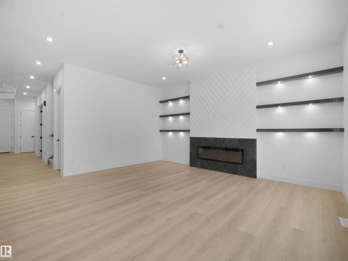 Unfurnished living room featuring light wood-type flooring, recessed lighting, and a tile fireplace - 1107 Gyrfalcon Crescent, Edmonton, AB - Indoor With Fireplace