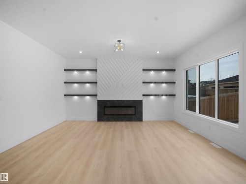 Unfurnished living room featuring light wood finished floors, a large fireplace, and recessed lighting - 1107 Gyrfalcon Crescent, Edmonton, AB - Indoor