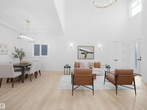 Living room featuring suspended lighting, light wood finished floors, and a high ceiling - 1168 Gyrfalcon Crescent, Edmonton, AB - Indoor Photo Showing Dining Room
