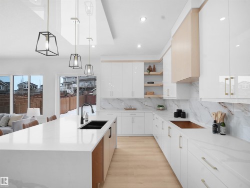 Dual tone kitchen with pendant lighting, light stone countertops, open shelves, modern cabinets, and dual tone cabinets - 1168 Gyrfalcon Crescent, Edmonton, AB - Indoor Photo Showing Kitchen With Double Sink With Upgraded Kitchen