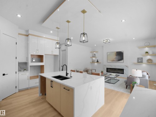 Kitchen featuring hanging light fixtures, a premium fireplace, light wood-style flooring, open floor plan, and white cabinets - 1168 Gyrfalcon Crescent, Edmonton, AB - Indoor Photo Showing Kitchen With Double Sink With Upgraded Kitchen