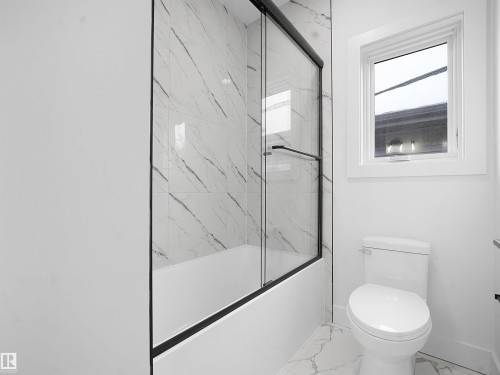Bathroom featuring bath / shower combo with glass door and marble finish floors - 1168 Gyrfalcon Crescent, Edmonton, AB - Indoor Photo Showing Bathroom