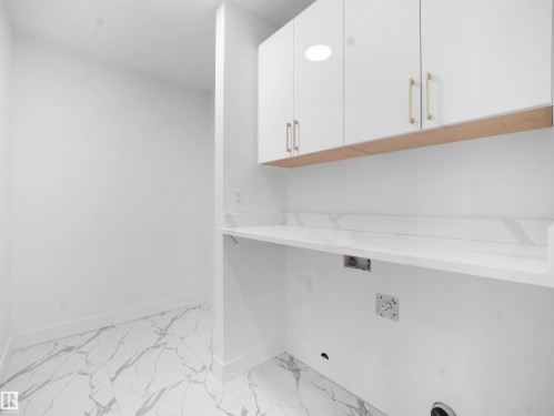 Laundry area with washer hookup, cabinet space, and light marble finish flooring - 1168 Gyrfalcon Crescent, Edmonton, AB - Indoor