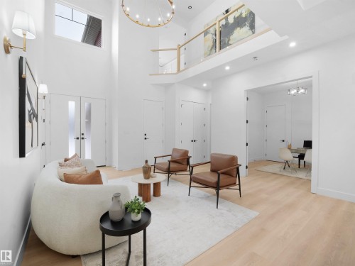 Living room with hanging lights, light wood-style floors, a high ceiling, french doors, and a desk - 1168 Gyrfalcon Crescent, Edmonton, AB - Indoor Photo Showing Other Room
