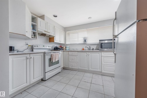 Kitchen featuring white appliances, white cabinets, light countertops, open shelves, and light tile patterned floors - 2831 36 Street, Edmonton, AB - Indoor Photo Showing Kitchen