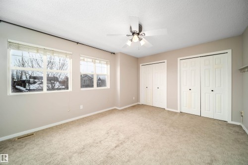 Unfurnished bedroom featuring multiple closets, carpet, a ceiling fan, and a textured ceiling - 1695 Tompkins Place, Edmonton, AB - Indoor Photo Showing Other Room