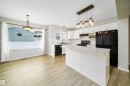 Kitchen with black appliances, white cabinetry, pendant lighting, light wood finished floors, and a kitchen island - 1695 Tompkins Place, Edmonton, AB  - Indoor Photo Showing Kitchen 