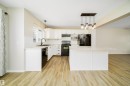 Kitchen featuring pendant lighting, white cabinets, black appliances, a textured ceiling, and a center island - 1695 Tompkins Place, Edmonton, AB  - Indoor Photo Showing Kitchen 