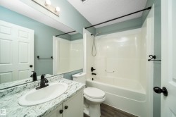 Bathroom featuring vanity, shower / bath combination, a textured ceiling, and dark wood finished floors - 