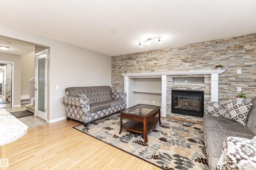 Living area featuring light wood-style flooring, a tiled fireplace, and a textured ceiling - 192 Keyport Circle, Leduc, AB - Indoor Photo Showing Living Room With Fireplace