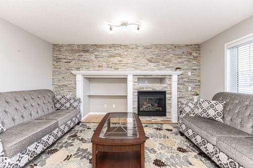 Living room with wood finished floors, a tile fireplace, and a textured ceiling - 192 Keyport Circle, Leduc, AB - Indoor Photo Showing Living Room With Fireplace