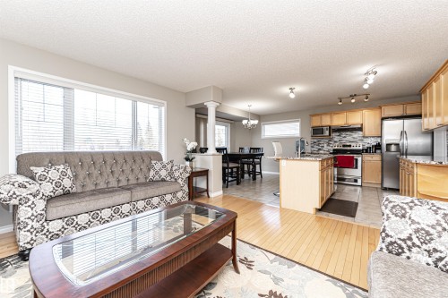 Living room featuring light wood finished floors, a textured ceiling, and a chandelier - 192 Keyport Circle, Leduc, AB - Indoor Photo Showing Living Room