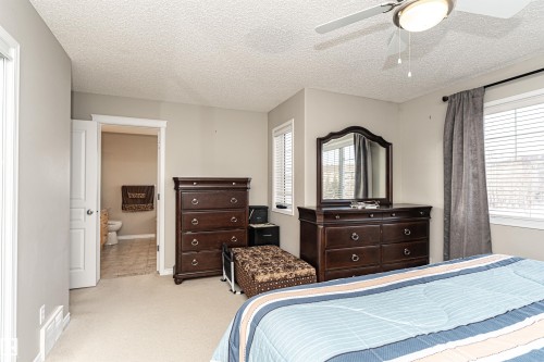 Bedroom with a textured ceiling, a ceiling fan, light colored carpet, and ensuite bath - 192 Keyport Circle, Leduc, AB - Indoor Photo Showing Bedroom