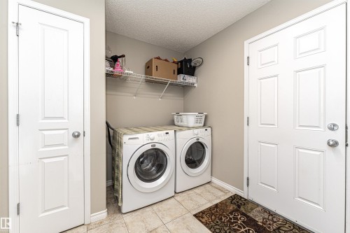 Laundry area with a textured ceiling, separate washer and dryer, and light tile patterned floors - 192 Keyport Circle, Leduc, AB - Indoor Photo Showing Laundry Room