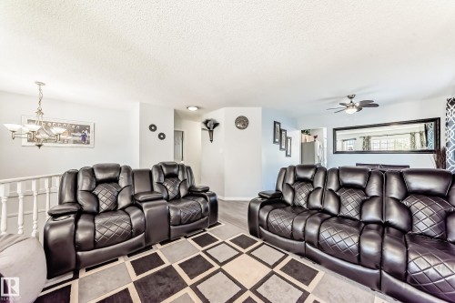 Living room featuring a textured ceiling, a chandelier, and a ceiling fan - 6 Jefferson Road, Edmonton, AB 