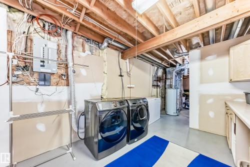 Laundry area featuring finished concrete flooring, separate washer and dryer, electric panel, and gas water heater - 6 Jefferson Road, Edmonton, AB 