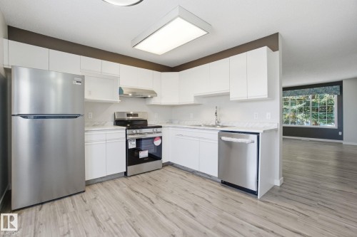 Kitchen with stainless steel appliances, white cabinets, and light wood-style flooring - 8006 15A Avenue, Edmonton, AB - Indoor Photo Showing Kitchen