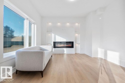 Sitting room featuring a glass covered fireplace and light wood finished floors - 235 Linden Loop, Leduc, AB - Indoor Photo Showing Living Room With Fireplace