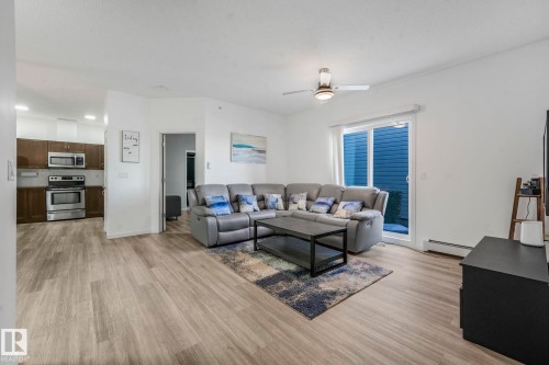 Living area with light wood finished floors, a baseboard radiator, and a ceiling fan - 419 396 Silverberry Road, Edmonton, AB - Indoor Photo Showing Living Room
