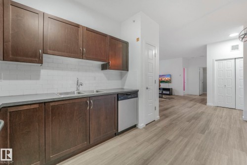 Kitchen with dark brown cabinets, dishwasher, decorative backsplash, and light wood-type flooring - 419 396 Silverberry Road, Edmonton, AB - Indoor Photo Showing Kitchen With Double Sink