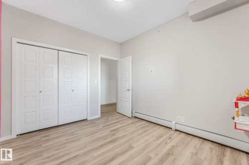 Unfurnished bedroom featuring a baseboard heating unit, light wood-style floors, a textured ceiling, and a closet - 419 396 Silverberry Road, Edmonton, AB - Indoor Photo Showing Other Room