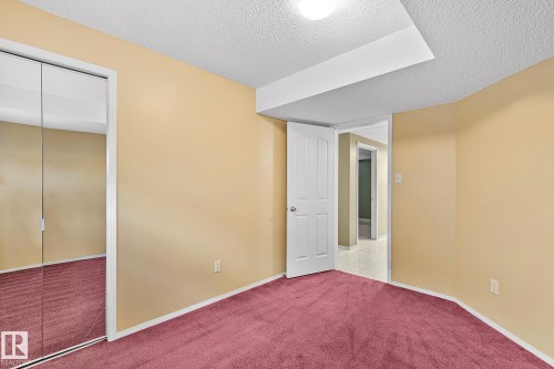 Unfurnished bedroom featuring a textured ceiling, carpet floors, and a closet - 2 Creekside Way, Spruce Grove, AB - Indoor Photo Showing Other Room