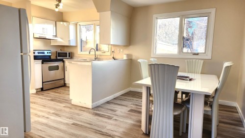 Kitchen featuring stainless steel appliances, light countertops, white cabinets, and light wood-style floors - 4709 106 Street, Edmonton, AB - Indoor