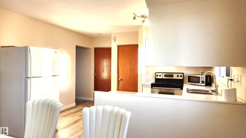 Kitchen with stainless steel appliances, white cabinetry, and light wood-type flooring - 4709 106 Street, Edmonton, AB - Indoor Photo Showing Kitchen