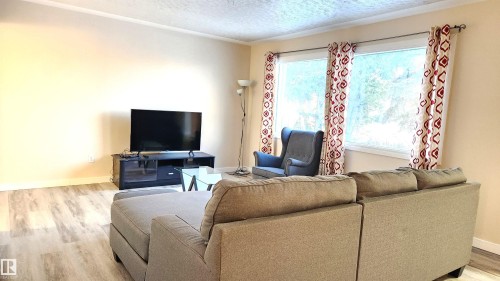 Living room with light wood finished floors and a textured ceiling - 4709 106 Street, Edmonton, AB - Indoor Photo Showing Living Room