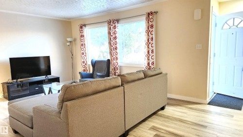 Living room featuring light wood finished floors and a textured ceiling - 4709 106 Street, Edmonton, AB - Indoor