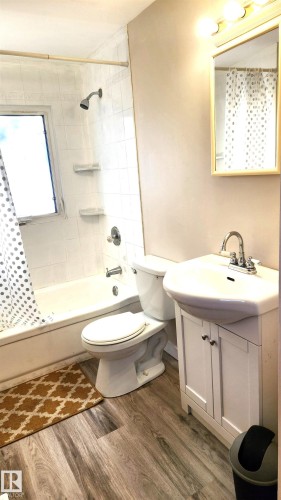 Bathroom with vanity, shower / tub combo with curtain, and dark wood-type flooring - 4709 106 Street, Edmonton, AB - Indoor Photo Showing Bathroom