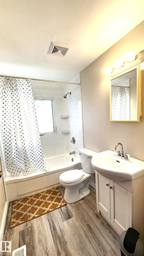Full bathroom featuring shower / bathtub combination with curtain, vanity, and light wood finished floors - 4709 106 Street, Edmonton, AB - Indoor Photo Showing Bathroom