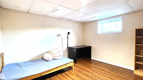 Bedroom featuring a drop ceiling and wood finished floors - 4709 106 Street, Edmonton, AB - Indoor