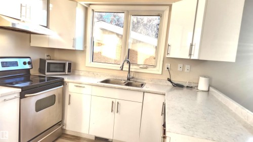 Kitchen featuring stainless steel appliances, light countertops, and white cabinets - 4709 106 Street, Edmonton, AB - Indoor Photo Showing Kitchen With Double Sink