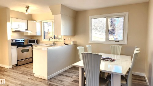 Kitchen with light countertops, stainless steel appliances, white cabinets, light wood-style floors, and a peninsula - 4709 106 Street, Edmonton, AB - Indoor