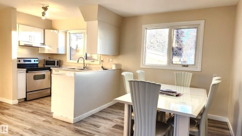 Kitchen featuring light countertops, stainless steel appliances, white cabinetry, light wood-style floors, and a peninsula - 4709 106 Street, Edmonton, AB - Indoor